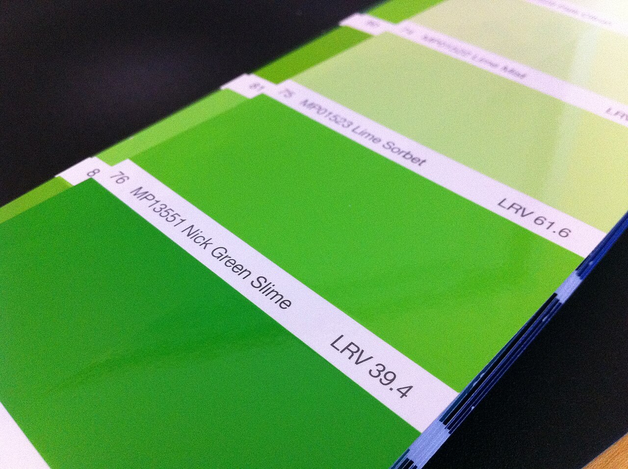 Paint color swatch cards fanned out in shades of green