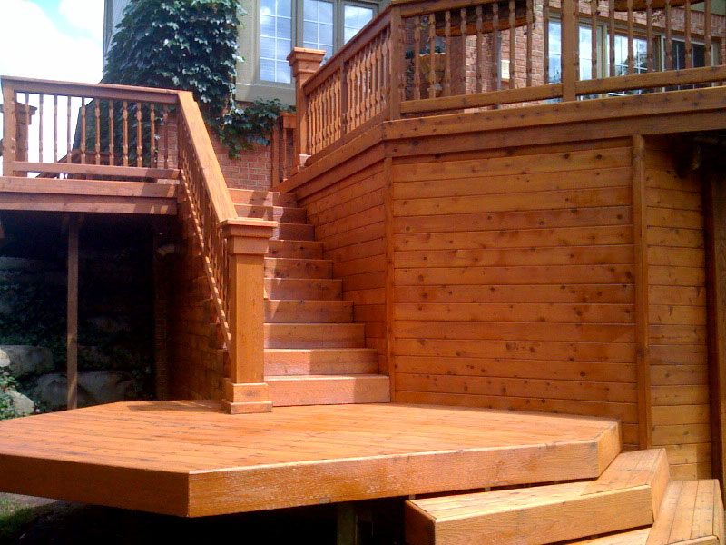 A freshly stained cedar deck with stairs and railing